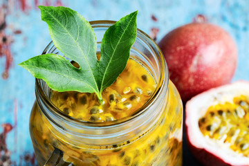 Passion fruit in a glass jar on blue wooden table close-up