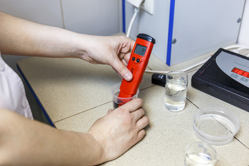 Scientists analysis with measuring pH in chemical biology laboratory with glassware equipment, female hands with pH meter
