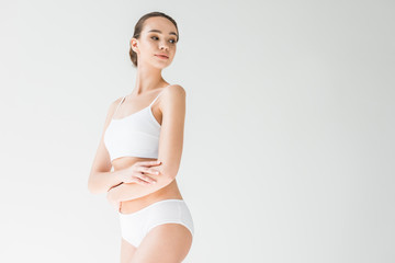 Fototapeta premium attractive caucasian woman in white lingerie with folded arms isolated on gray background
