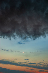 A huge cloud over the setting sun and the moon