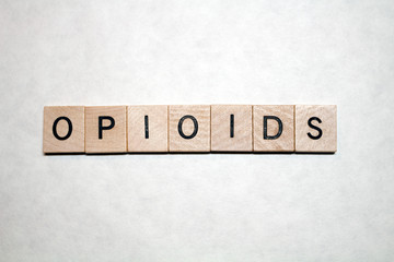 Opioids written on wooden blocks with black letters on a white background. Concepts of drug abuse, opioid crisis, prescription drugs