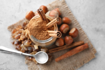 Jar with cinnamon and hazelnuts on light table