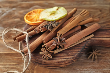 Board with aromatic cinnamon sticks on wooden background