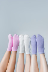 partial view of female legs in different colorful socks isolated on gray background