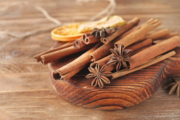 Board with aromatic cinnamon sticks on wooden background