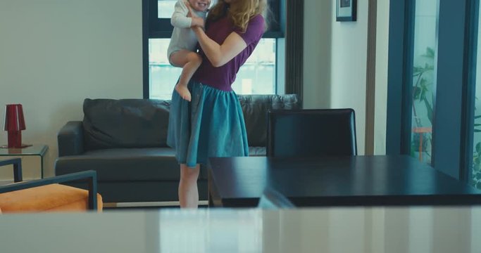 Mother spinning her toddler around in a city apartment