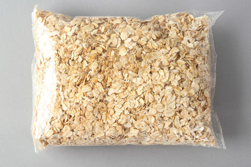 Package with raw oatmeal on light background