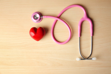 Red heart and stethoscope on wooden background. Health care concept