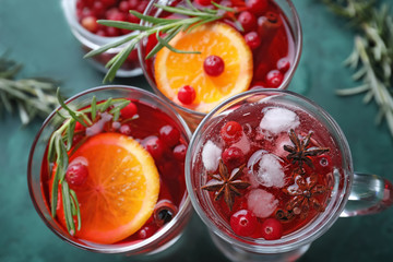 Tasty beverages with cranberry and spices in glasses on table