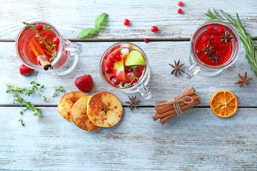 Tasty beverages with cranberry and cinnamon in glass cups on table