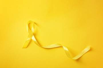 Yellow ribbon on color background. Cancer concept - obrazy, fototapety, plakaty
