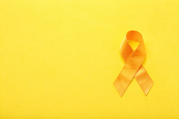 Yellow ribbon on color background. Cancer concept