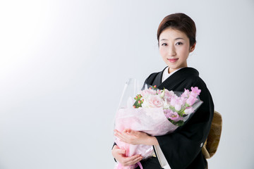 花束を持つ黒留袖の女性
