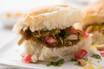 Dabeli is an Indian snack item served with Pomegranate Seeds and Cilantro in white ceramic plate. It's a popular Navratri Festival food