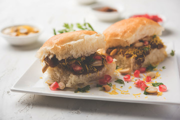 Dabeli is an Indian snack item served with Pomegranate Seeds and Cilantro in white ceramic plate. It's a popular Navratri Festival food