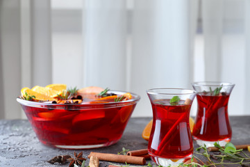 Tasty drink with cinnamon sticks and orange slices in glassware on table