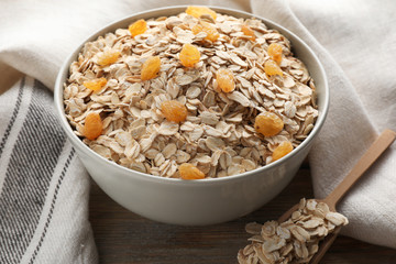 Bowl with oat flakes and raisins on wooden table