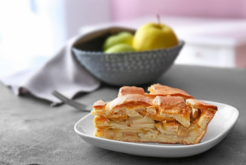 Plate with piece of delicious apple pie on table