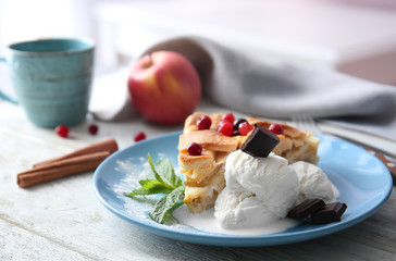 Plate with piece of delicious apple pie and ice cream on wooden table