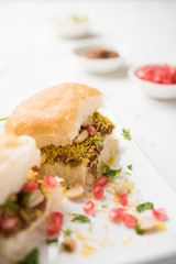 Dabeli is an Indian snack item served with Pomegranate Seeds and Cilantro in white ceramic plate. It's a popular Navratri Festival food