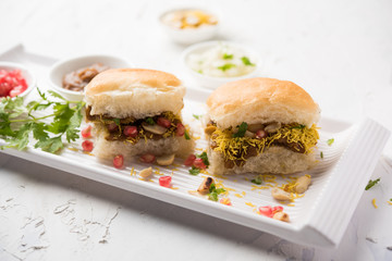 Dabeli is an Indian snack item served with Pomegranate Seeds and Cilantro in white ceramic plate. It's a popular Navratri Festival food