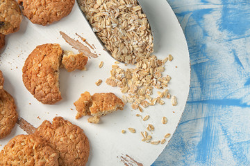 Stand with delicious cookies and oatmeal on color background, top view