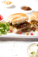Dabeli is an Indian snack item served with Pomegranate Seeds and Cilantro in white ceramic plate. It's a popular Navratri Festival food