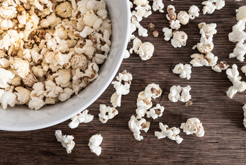 top view close-up of bowl filled with popcorn on rustic wooden table