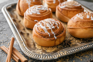 Tray with delicious cinnamon buns on dark background, closeup
