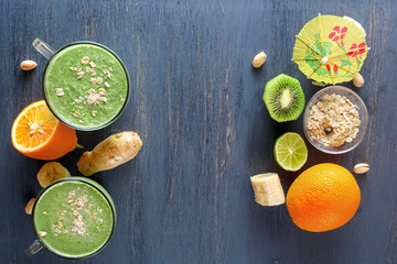 Fresh green smoothies in a glass mug on a wooden table with vegetables, fruits and oat chlorine on a wooden table. Top view. The concept of a healthy diet. Copy space
