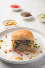 Dabeli is an Indian snack item served with Pomegranate Seeds and Cilantro in white ceramic plate. It's a popular Navratri Festival food
