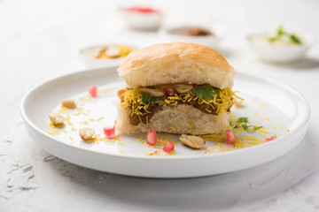 Dabeli is an Indian snack item served with Pomegranate Seeds and Cilantro in white ceramic plate. It's a popular Navratri Festival food