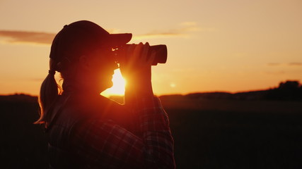 A woman looking through binoculars at sunset. Travel and safari concept © StockMediaSeller