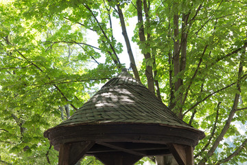 Roof of a gazebo in a park under green trees