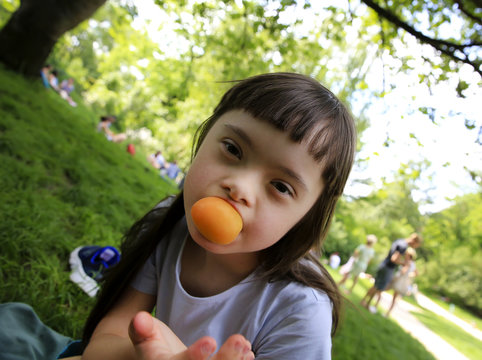 Young girl eating apricot in the park