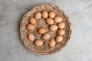 Many eggs in a basket on a cement floor.