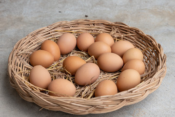 Many eggs in a basket on a cement floor.
