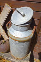 Obraz premium Old milk jug on the wooden wall of a shed in bright sunlight