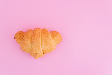 Fresh croissant on pink background