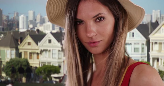 Close-up of stylish hipster girl looking at camera near painted ladies houses, Portrait of pretty millennial Caucasian girl in her 20s outside in San Francisco, 4k