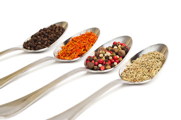 Different spices in iron spoons isolated on white