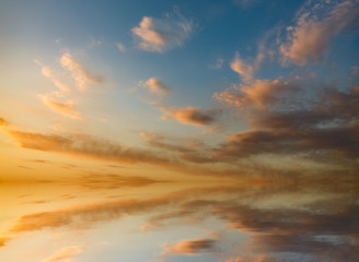 Dramatic sunset with dark orange clouds reflected in water.