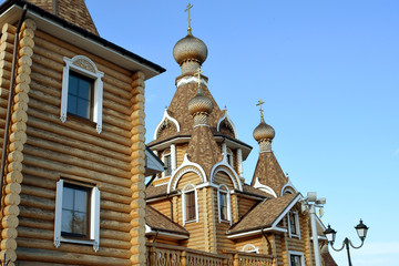Fototapeta na wymiar Wooden Orthodox temple from the uneven bars against the blue sky.