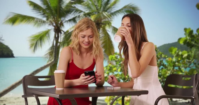 Portrait of two lovely young women looking at cellphone in summer dresses on Caribbean beach, Couple of cute girls sharing smart phone in the Bahamas, 4k