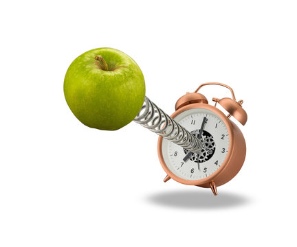 Green apple springing out of alarm clock isolated on white background