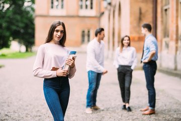 Fototapeta premium Smiling female student with folders and group in the back
