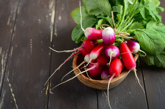 Bunch of fresh colorful radishes on old rustic wooden table, selective focus, copy space.