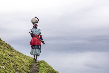 Einheimische schwarze Afrikanerin trägt in den Hügeln Südafrikas eine Last auf dem Kopf