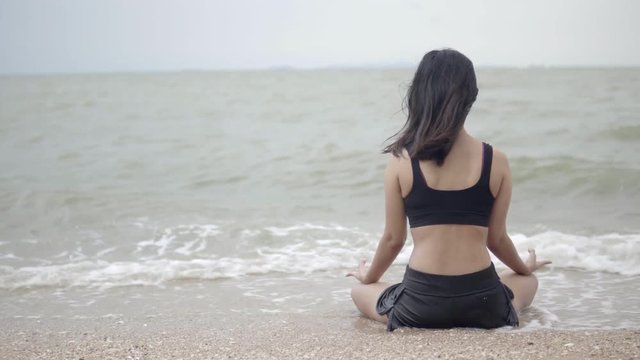 Young asia woman practicing yoga on the beach.4K Resolution