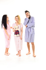 Man with beard and mustache, cute blonde and brunette girls with toy bear just wake up. Girls with bearded macho in pajamas and robe in morning, isolated white background. Sleepy morning concept.